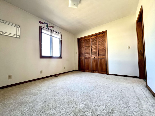 unfurnished bedroom featuring a closet, visible vents, light colored carpet, and baseboards