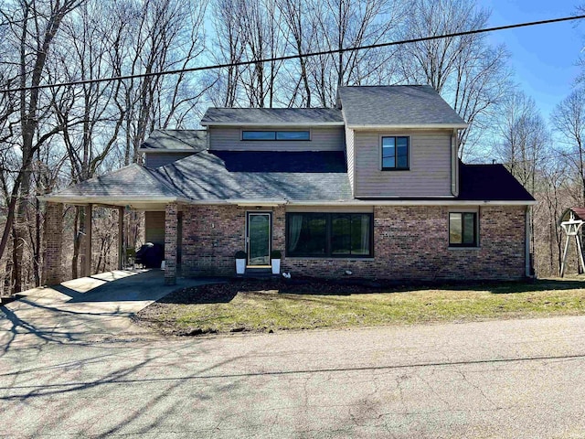 view of front of property with an attached carport, a front lawn, brick siding, and driveway