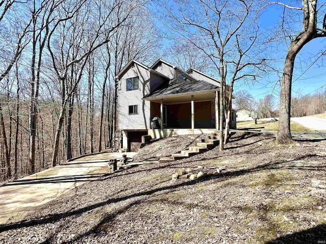 view of front of house featuring stairway and roof with shingles