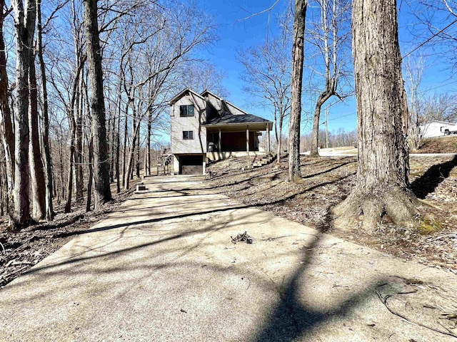 rear view of property with a gambrel roof and driveway