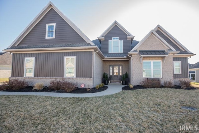 craftsman inspired home with brick siding, a shingled roof, and a front yard