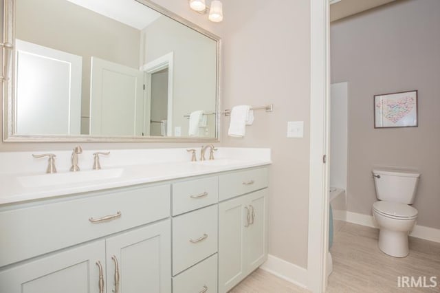 full bath with a sink, baseboards, toilet, and double vanity