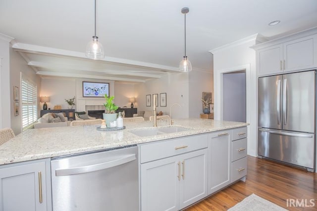 kitchen with wood finished floors, a sink, appliances with stainless steel finishes, decorative light fixtures, and open floor plan