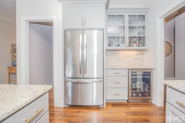 kitchen featuring beverage cooler, light wood finished floors, glass insert cabinets, and freestanding refrigerator