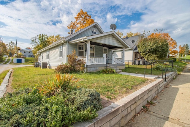 bungalow-style house with central air condition unit, a porch, a front lawn, and fence