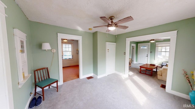 living area with carpet flooring, baseboards, and a textured ceiling