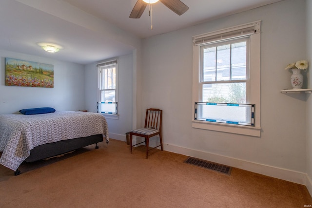 bedroom with ceiling fan, light colored carpet, visible vents, and baseboards