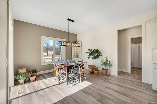 dining space with a chandelier, light wood-style flooring, and baseboards