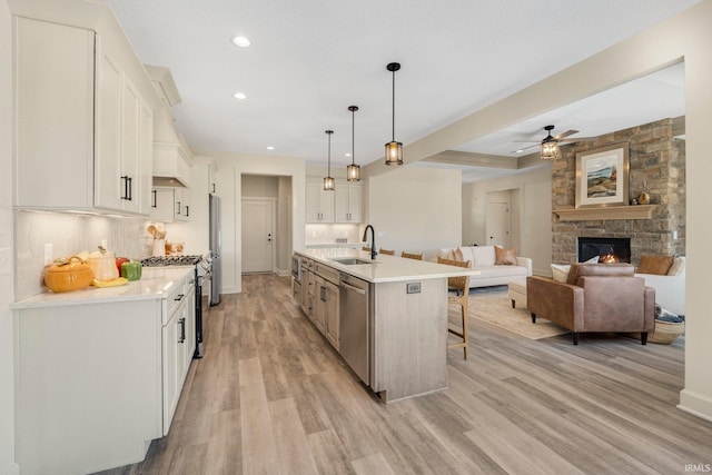 kitchen with a kitchen bar, light wood-style flooring, a sink, white cabinetry, and stainless steel appliances