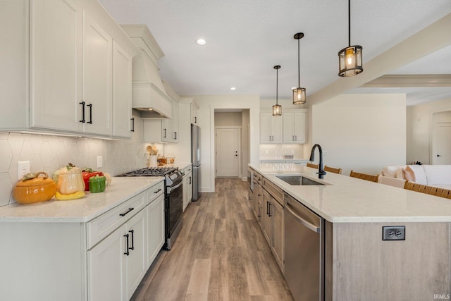 kitchen featuring a large island, a sink, appliances with stainless steel finishes, light wood finished floors, and decorative backsplash