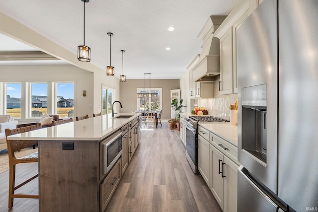 kitchen with a kitchen bar, a sink, tasteful backsplash, wood finished floors, and appliances with stainless steel finishes