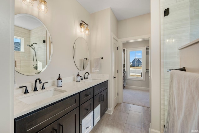 full bath with double vanity, baseboards, a tile shower, and a sink