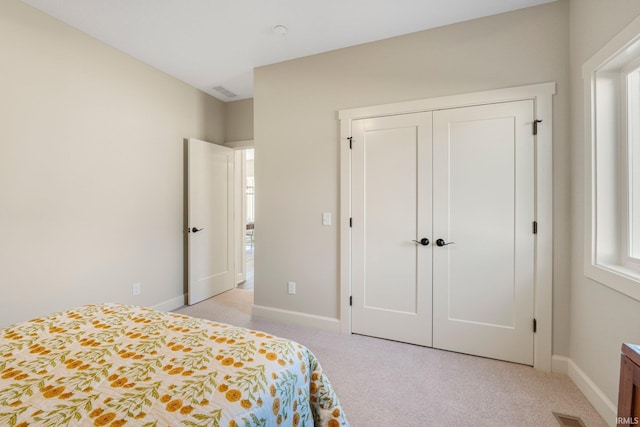 bedroom featuring visible vents, baseboards, a closet, and light carpet