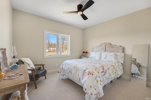 bedroom featuring baseboards, light colored carpet, and a ceiling fan