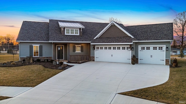 view of front of property featuring stone siding, an attached garage, driveway, and a front yard