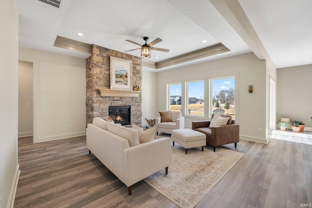 living room with a fireplace, baseboards, a tray ceiling, and wood finished floors