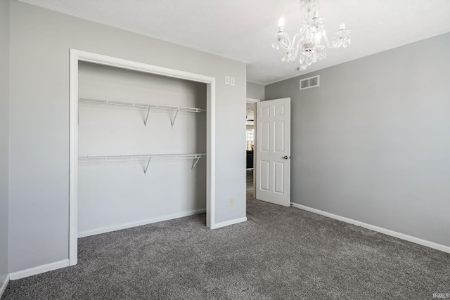 unfurnished bedroom with visible vents, a closet, carpet, an inviting chandelier, and baseboards