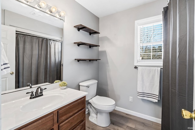 bathroom featuring vanity, toilet, wood finished floors, and baseboards