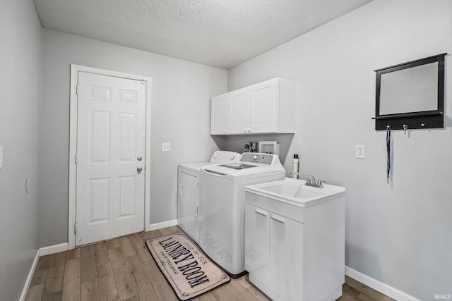 laundry room with light wood finished floors, cabinet space, baseboards, and separate washer and dryer