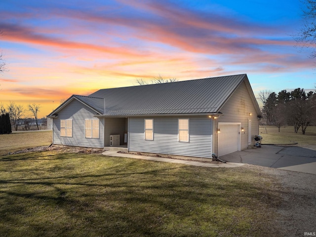 view of front of property featuring a front yard, metal roof, driveway, an attached garage, and a standing seam roof