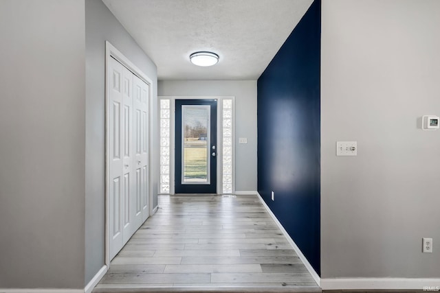 foyer entrance with wood finished floors, baseboards, and a textured ceiling