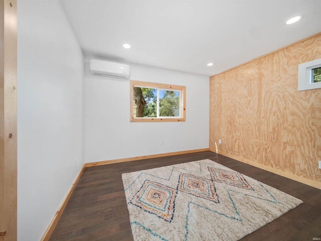 empty room featuring recessed lighting, baseboards, a wall unit AC, and dark wood-style flooring