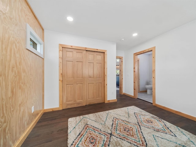 unfurnished bedroom with dark wood finished floors, recessed lighting, ensuite bathroom, and baseboards