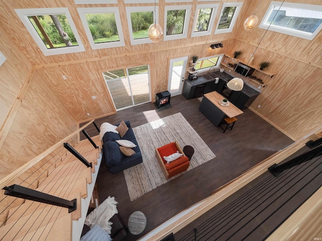 living room with wood finished floors, wooden walls, and a towering ceiling