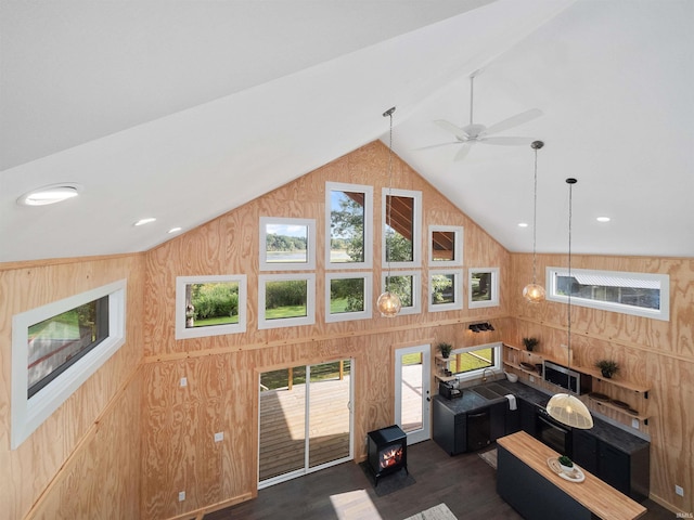 living area with high vaulted ceiling, a ceiling fan, recessed lighting, wood walls, and dark wood-style flooring