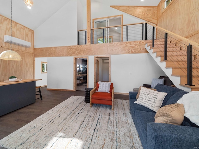 living area featuring high vaulted ceiling, an AC wall unit, wood finished floors, and stairs