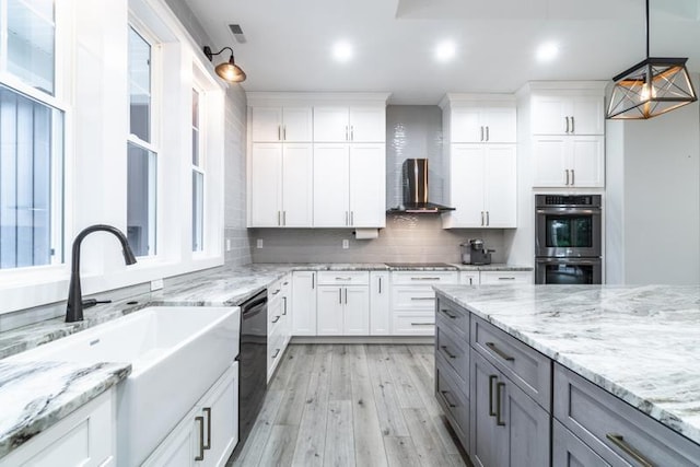 kitchen with gray cabinetry, decorative backsplash, black appliances, wall chimney exhaust hood, and a sink