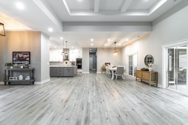 kitchen featuring light wood finished floors, baseboards, open floor plan, light countertops, and white cabinetry