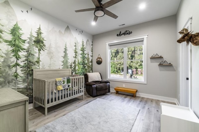 bedroom with a ceiling fan, visible vents, baseboards, light wood finished floors, and a nursery area