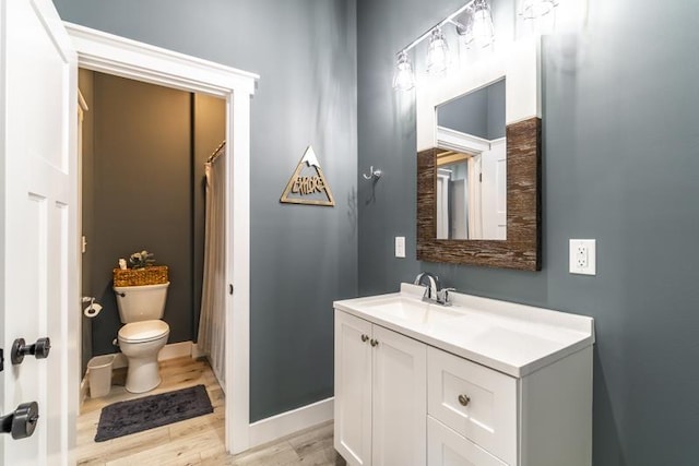 full bathroom with toilet, vanity, baseboards, and wood finished floors