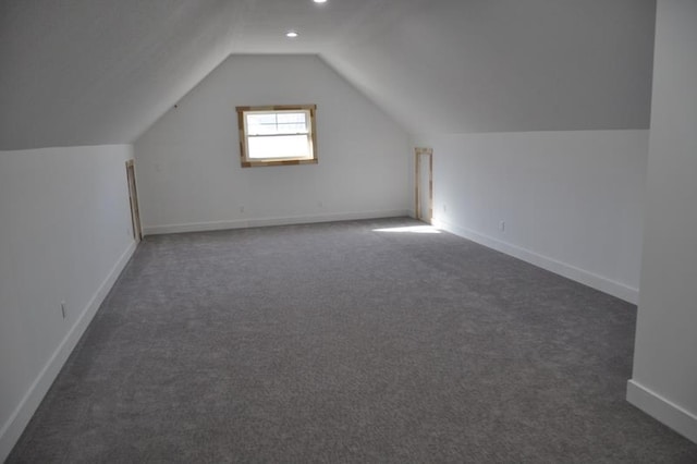 bonus room with dark colored carpet, baseboards, and lofted ceiling