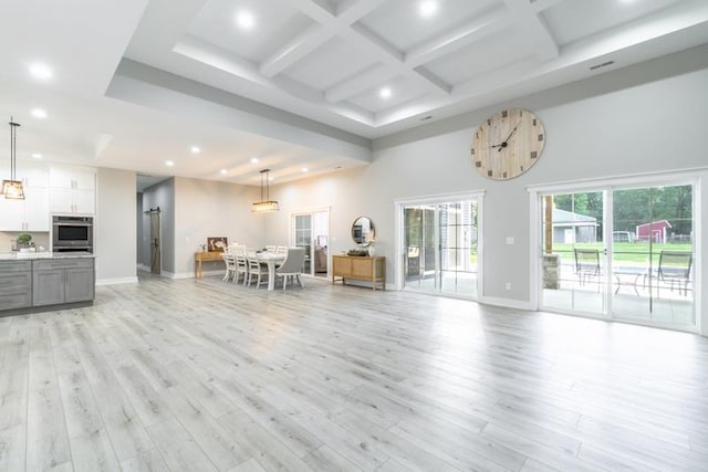 unfurnished living room featuring light wood finished floors, baseboards, recessed lighting, a high ceiling, and coffered ceiling