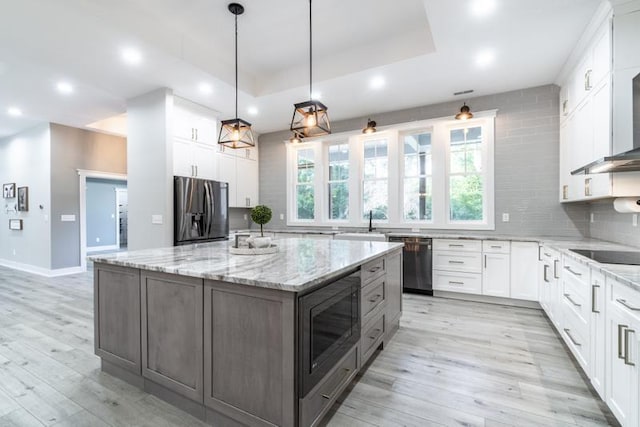 kitchen with backsplash, light wood-style floors, appliances with stainless steel finishes, white cabinets, and a raised ceiling