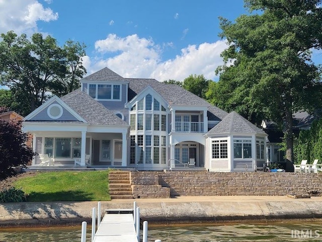 back of property with a balcony and a water view