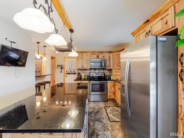 kitchen with light brown cabinets, dark stone countertops, appliances with stainless steel finishes, decorative backsplash, and hanging light fixtures