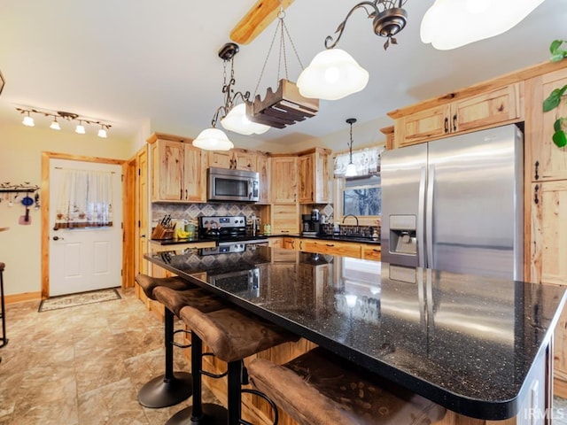 kitchen featuring a sink, decorative backsplash, light brown cabinetry, appliances with stainless steel finishes, and decorative light fixtures