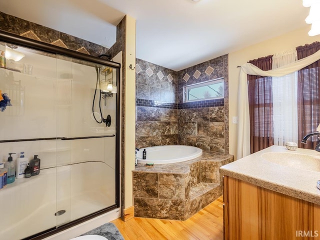 bathroom featuring a stall shower, vanity, a garden tub, and wood finished floors