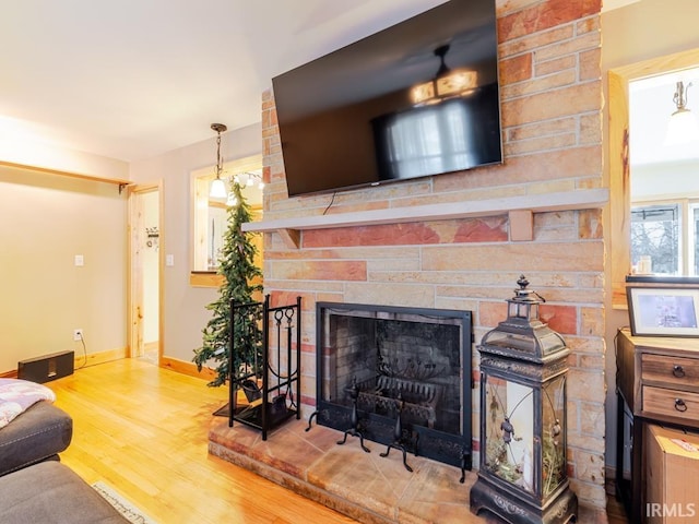 living room with a stone fireplace, wood finished floors, and baseboards