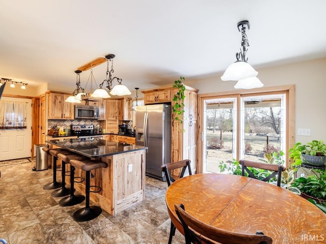 kitchen featuring a kitchen island, stainless steel appliances, decorative backsplash, pendant lighting, and a kitchen bar