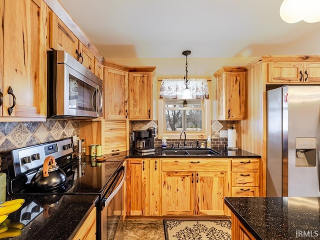 kitchen with dark stone counters, tasteful backsplash, appliances with stainless steel finishes, and a sink