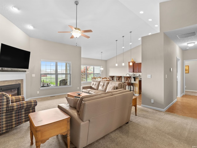 living area featuring high vaulted ceiling, light colored carpet, baseboards, and a tile fireplace