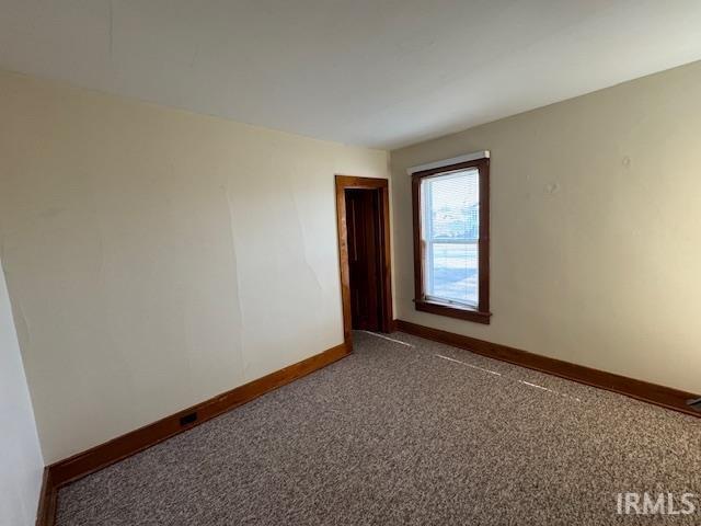 spare room featuring baseboards and carpet flooring