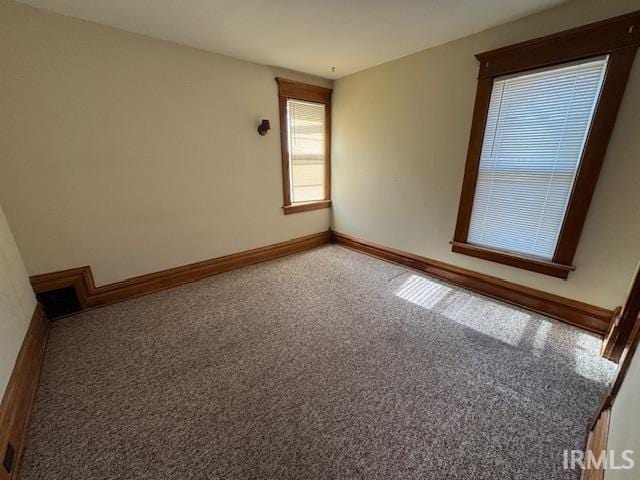 spare room featuring carpet and baseboards