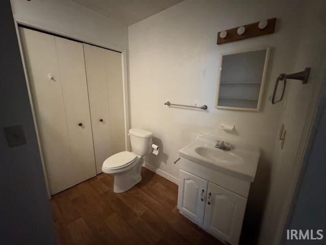 bathroom with baseboards, toilet, wood finished floors, and vanity