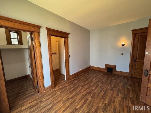 spare room with baseboards and dark wood-style flooring