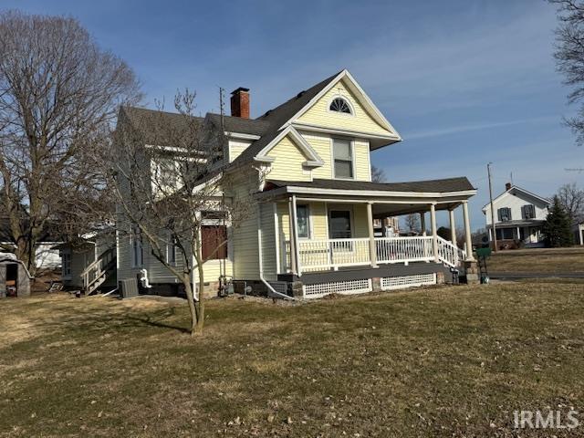 view of front of house featuring a front lawn, covered porch, central AC, and a chimney